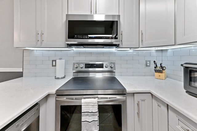 kitchen featuring appliances with stainless steel finishes, white cabinets, and tasteful backsplash