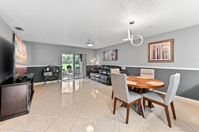 dining room featuring light tile patterned floors, baseboards, visible vents, and a textured ceiling