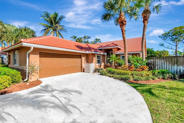 1075 E Lancewood Pl, Delray Beach, FL 33445 - mediterranean / spanish-style home with fence, a garage, stucco siding, a tiled roof, and driveway