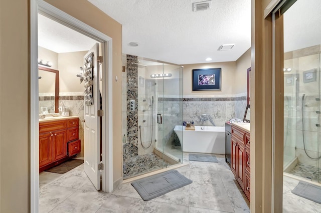 1075 E Lancewood Pl, Delray Beach, FL 33445 - bathroom with tile walls, vanity, a stall shower, a freestanding tub, and a textured ceiling