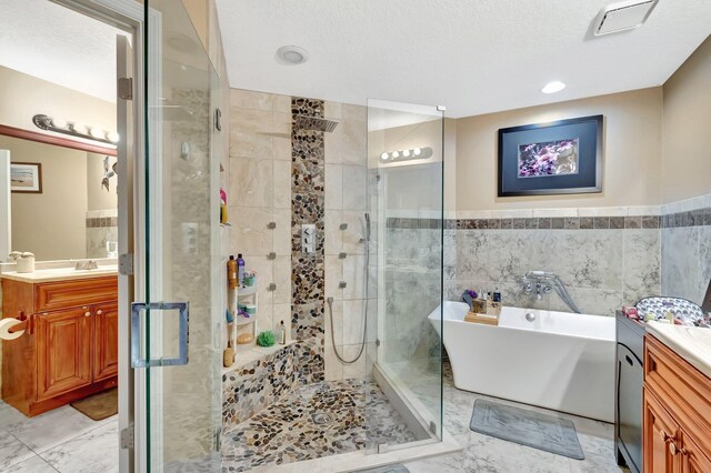 1075 E Lancewood Pl, Delray Beach, FL 33445 - bathroom featuring vanity, a stall shower, a freestanding tub, tile walls, and a textured ceiling