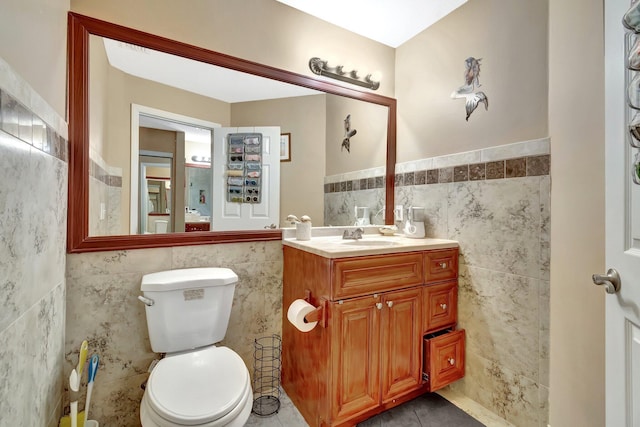 1075 E Lancewood Pl, Delray Beach, FL 33445 - half bathroom with tile walls, toilet, vanity, tile patterned flooring, and wainscoting