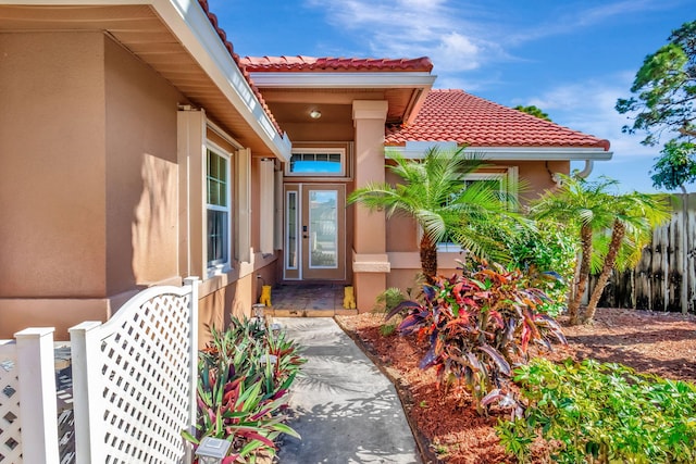 1075 E Lancewood Pl, Delray Beach, FL 33445 - property entrance with stucco siding, a tiled roof, and fence