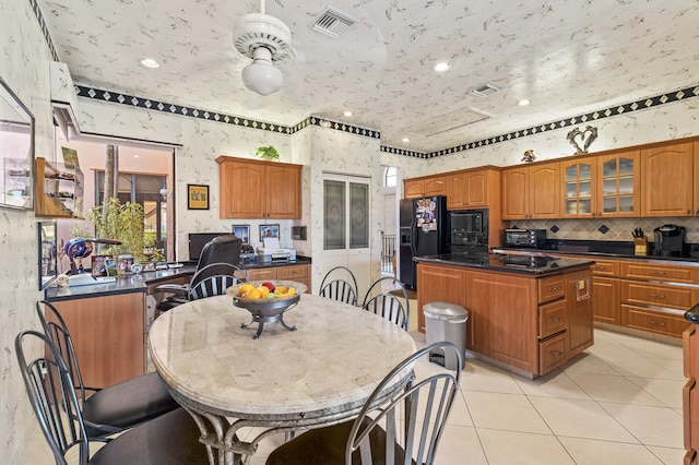 6525 Via Benita, Boca Raton, FL 33433 - kitchen with dark countertops, a kitchen island, brown cabinets, and black appliances