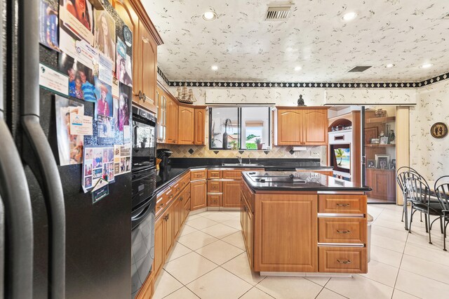 6525 Via Benita, Boca Raton, FL 33433 - kitchen featuring dark countertops, black oven, light tile patterned floors, and stainless steel fridge