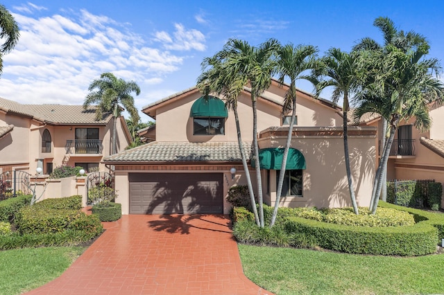 mediterranean / spanish home with a garage, decorative driveway, a tile roof, and stucco siding