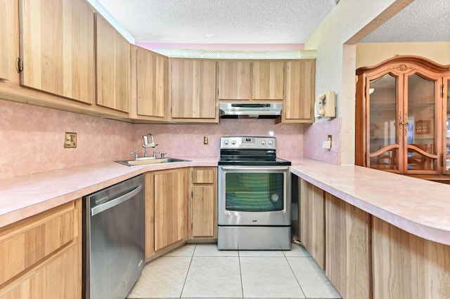 kitchen featuring sink, decorative backsplash, light tile patterned floors, stainless steel appliances, and a textured ceiling