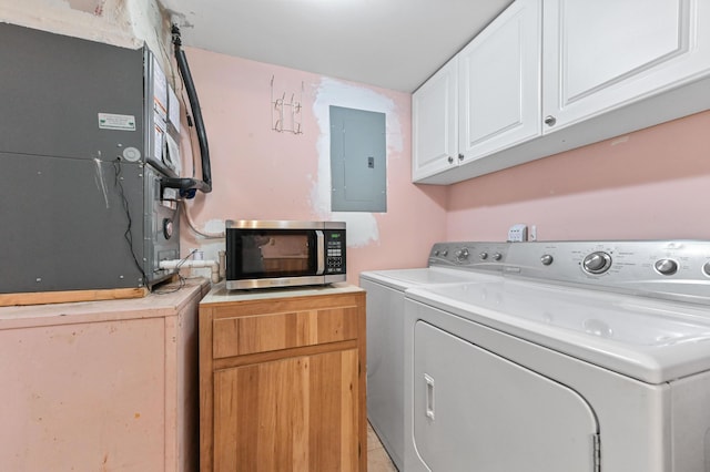 laundry room featuring heating unit, cabinets, electric panel, and washer and dryer