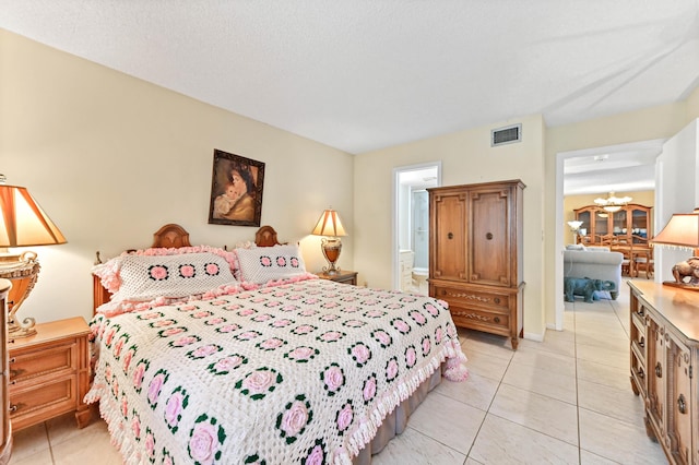 bedroom featuring light tile patterned floors, ensuite bath, a notable chandelier, and a textured ceiling