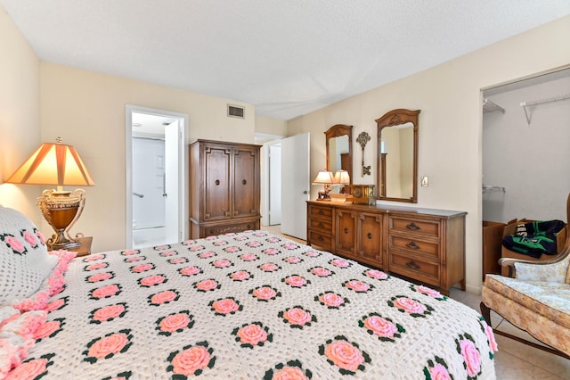 carpeted bedroom featuring ensuite bathroom, a spacious closet, and a textured ceiling