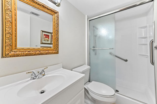 bathroom with vanity, a shower with door, and toilet