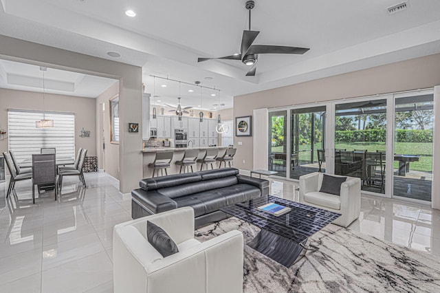 living room with a tray ceiling and ceiling fan