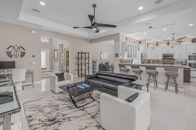 living room with ceiling fan and a tray ceiling