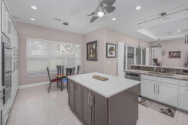 kitchen featuring appliances with stainless steel finishes, pendant lighting, sink, a center island, and ceiling fan