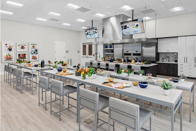 kitchen with a paneled ceiling, built in fridge, decorative backsplash, and a high ceiling