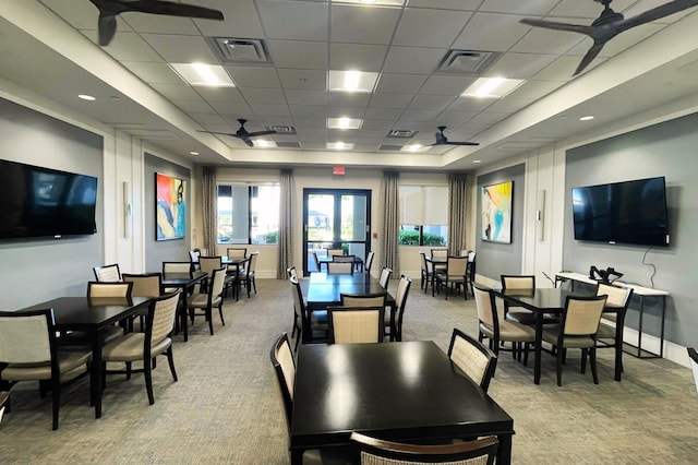 carpeted dining room with a raised ceiling, a paneled ceiling, and ceiling fan