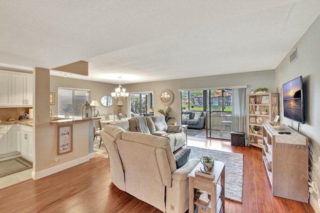 living room with an inviting chandelier and light hardwood / wood-style flooring