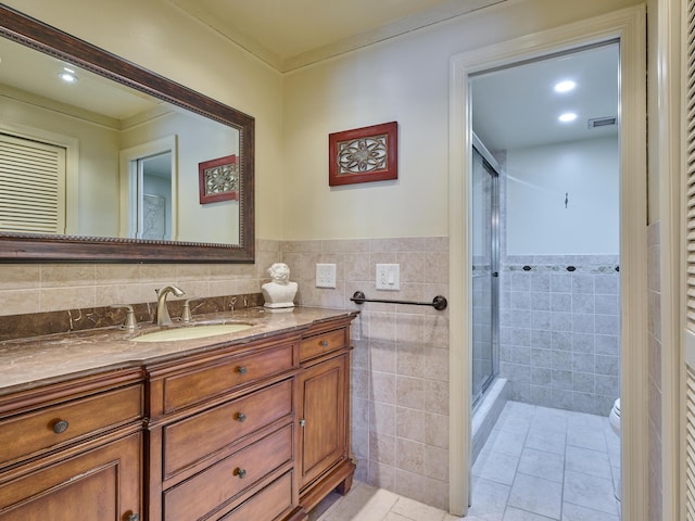 bathroom featuring tile walls, vanity, a shower with shower door, tile patterned floors, and toilet