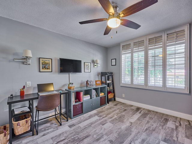 home office with ceiling fan, light hardwood / wood-style flooring, and a textured ceiling