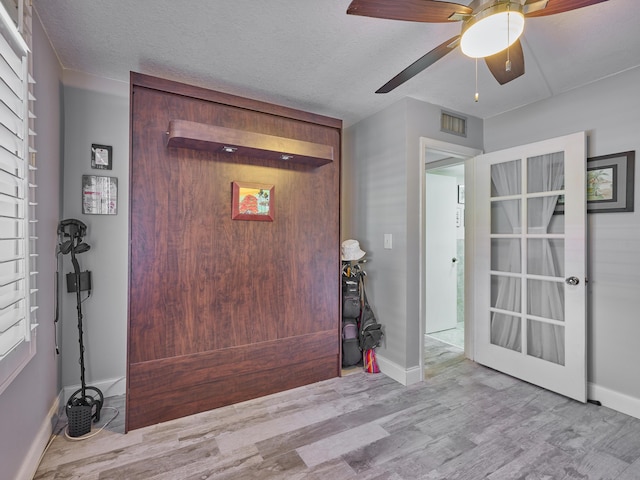 foyer entrance featuring ceiling fan, a textured ceiling, and light hardwood / wood-style flooring