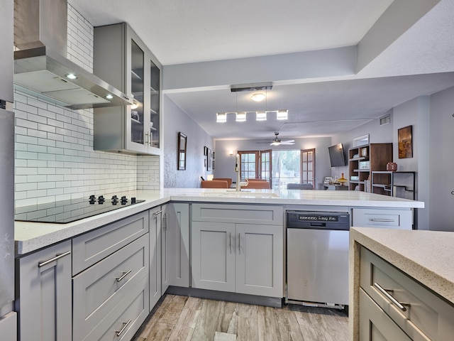 kitchen with gray cabinets, black electric stovetop, stainless steel dishwasher, kitchen peninsula, and wall chimney exhaust hood