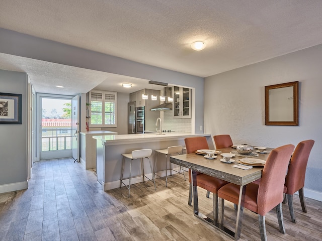 dining area with sink, light hardwood / wood-style floors, and a textured ceiling