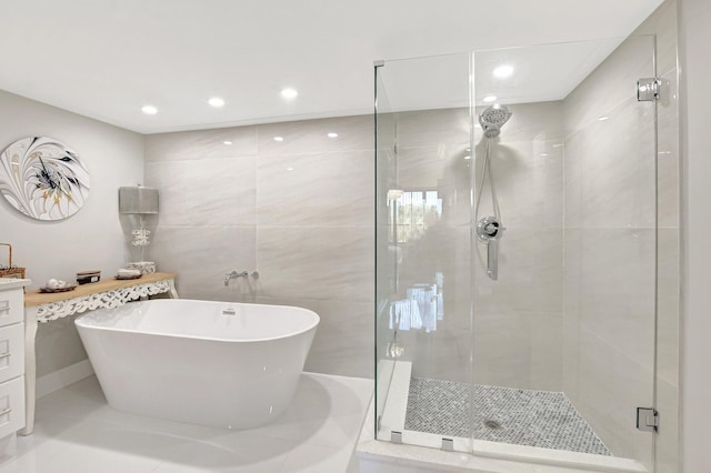 bathroom with vanity, tile walls, and separate shower and tub