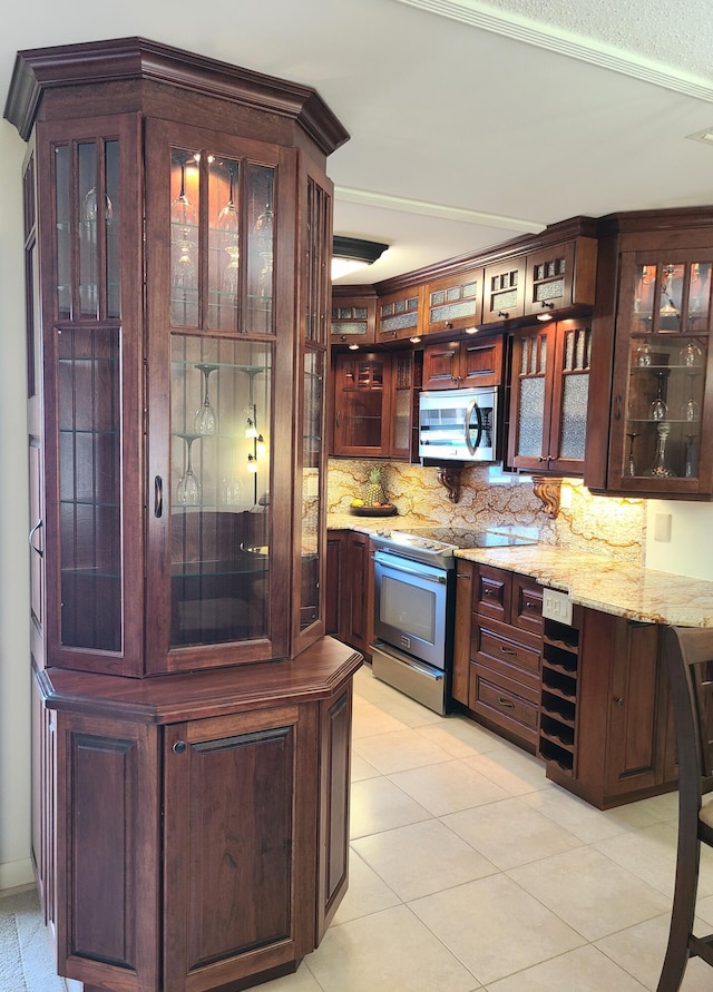 bar featuring light stone counters, tasteful backsplash, light tile patterned flooring, and appliances with stainless steel finishes