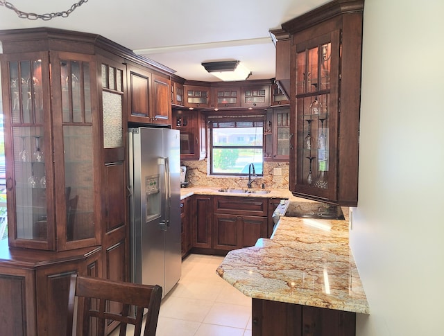 kitchen with sink, stainless steel fridge with ice dispenser, dark brown cabinets, light stone countertops, and decorative backsplash