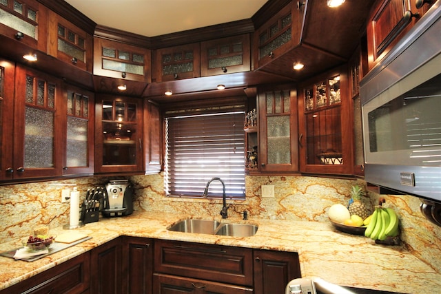 kitchen featuring light stone counters, sink, backsplash, and range