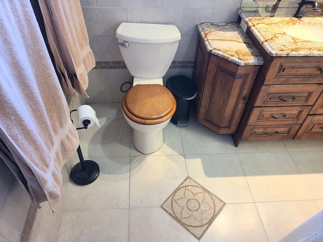 bathroom with tile patterned flooring, vanity, tile walls, and toilet