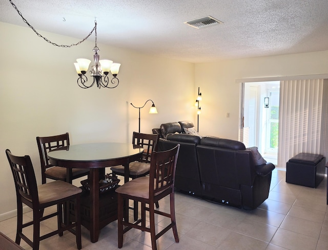 tiled dining area with a chandelier and a textured ceiling