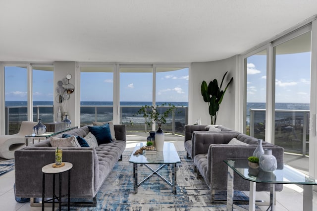 living room with light tile patterned flooring, a water view, a wealth of natural light, and expansive windows