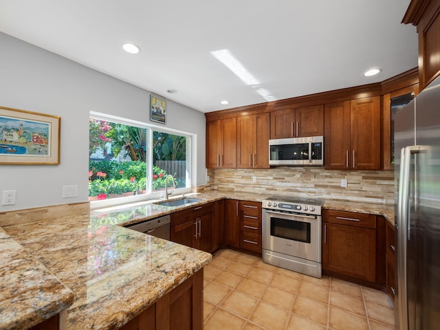 kitchen with appliances with stainless steel finishes, tasteful backsplash, sink, light stone counters, and kitchen peninsula