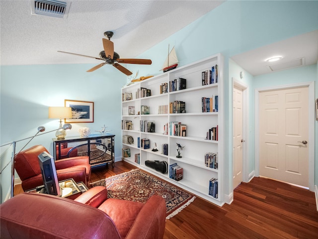 living area with dark wood-type flooring, ceiling fan, lofted ceiling, and a textured ceiling