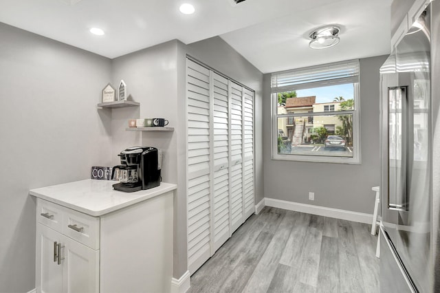 kitchen with high end fridge, light stone counters, hanging light fixtures, light hardwood / wood-style floors, and white cabinets