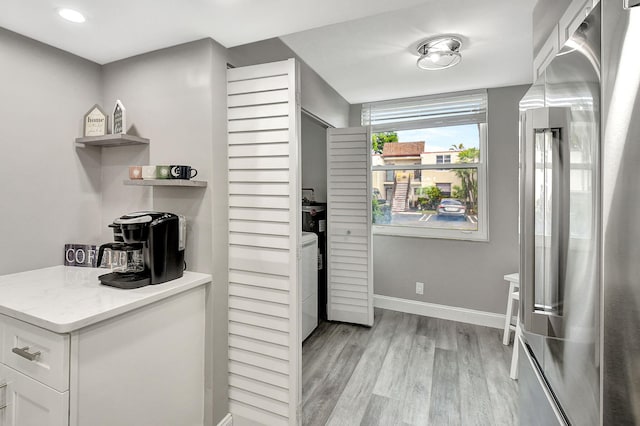 kitchen featuring washer / clothes dryer, high quality fridge, white cabinets, and light wood-type flooring