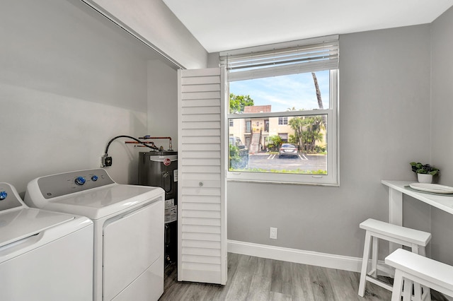 washroom with electric water heater, light hardwood / wood-style floors, and washing machine and dryer