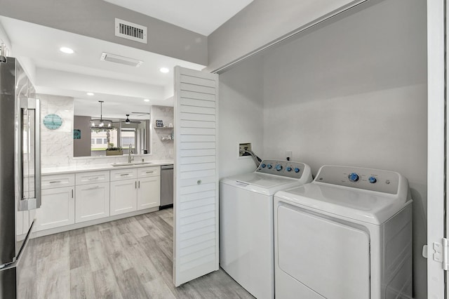 laundry room with ceiling fan, light hardwood / wood-style floors, sink, and washer and dryer