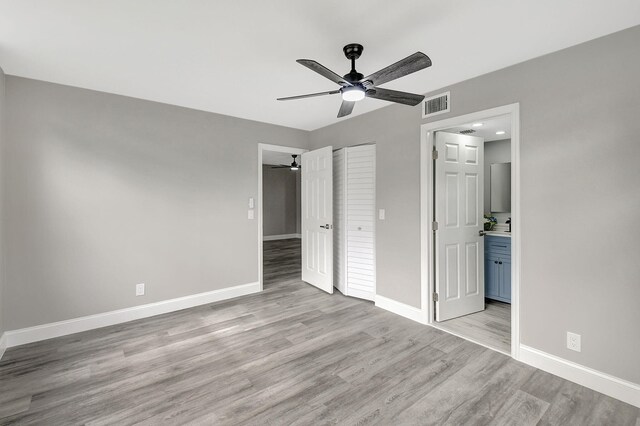 unfurnished bedroom with ensuite bathroom, ceiling fan, light hardwood / wood-style floors, and a closet