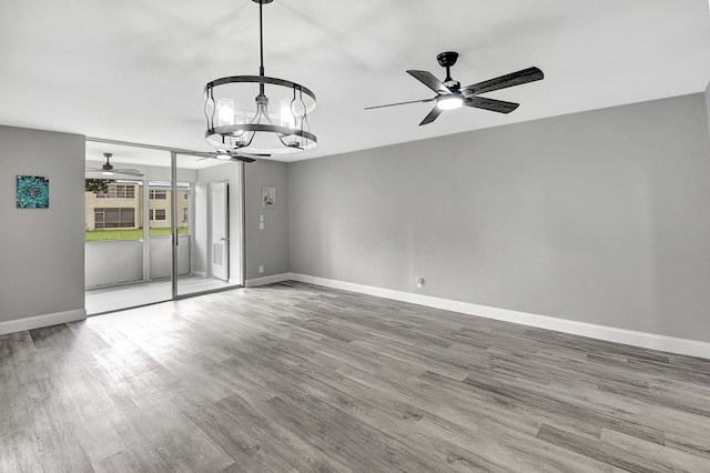 spare room featuring hardwood / wood-style flooring and ceiling fan with notable chandelier