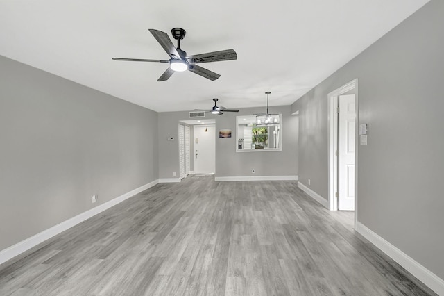 unfurnished living room with ceiling fan with notable chandelier and light hardwood / wood-style flooring