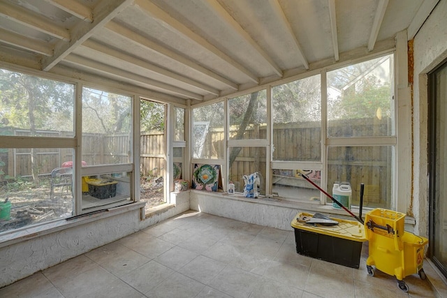 unfurnished sunroom featuring beamed ceiling and plenty of natural light