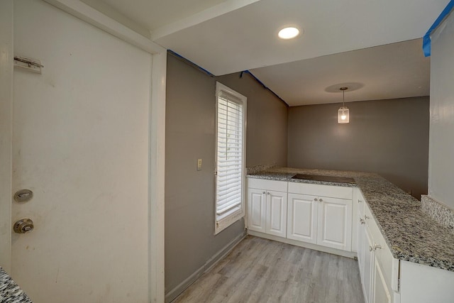 kitchen with kitchen peninsula, white cabinets, light wood-type flooring, and decorative light fixtures