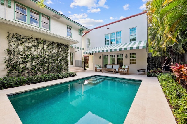 rear view of property featuring a patio area, an outdoor living space, a fenced in pool, and stucco siding