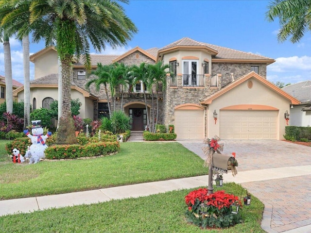 mediterranean / spanish house with a balcony, stone siding, decorative driveway, and stucco siding