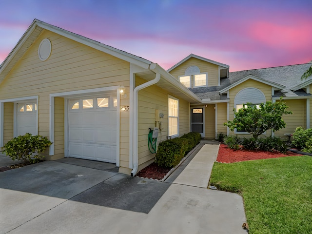 view of front of house with a front yard, an attached garage, a shingled roof, and driveway