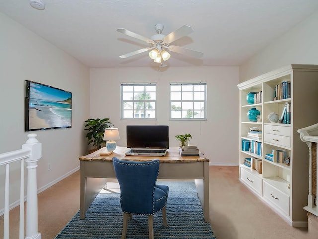 office space with a ceiling fan, light carpet, and baseboards