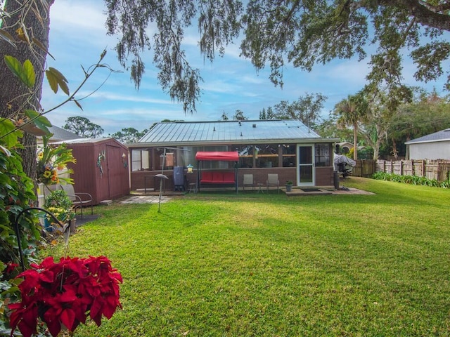 back of property featuring a storage unit, a sunroom, and a lawn