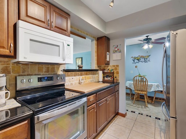 kitchen with backsplash, light tile patterned floors, ceiling fan, and appliances with stainless steel finishes